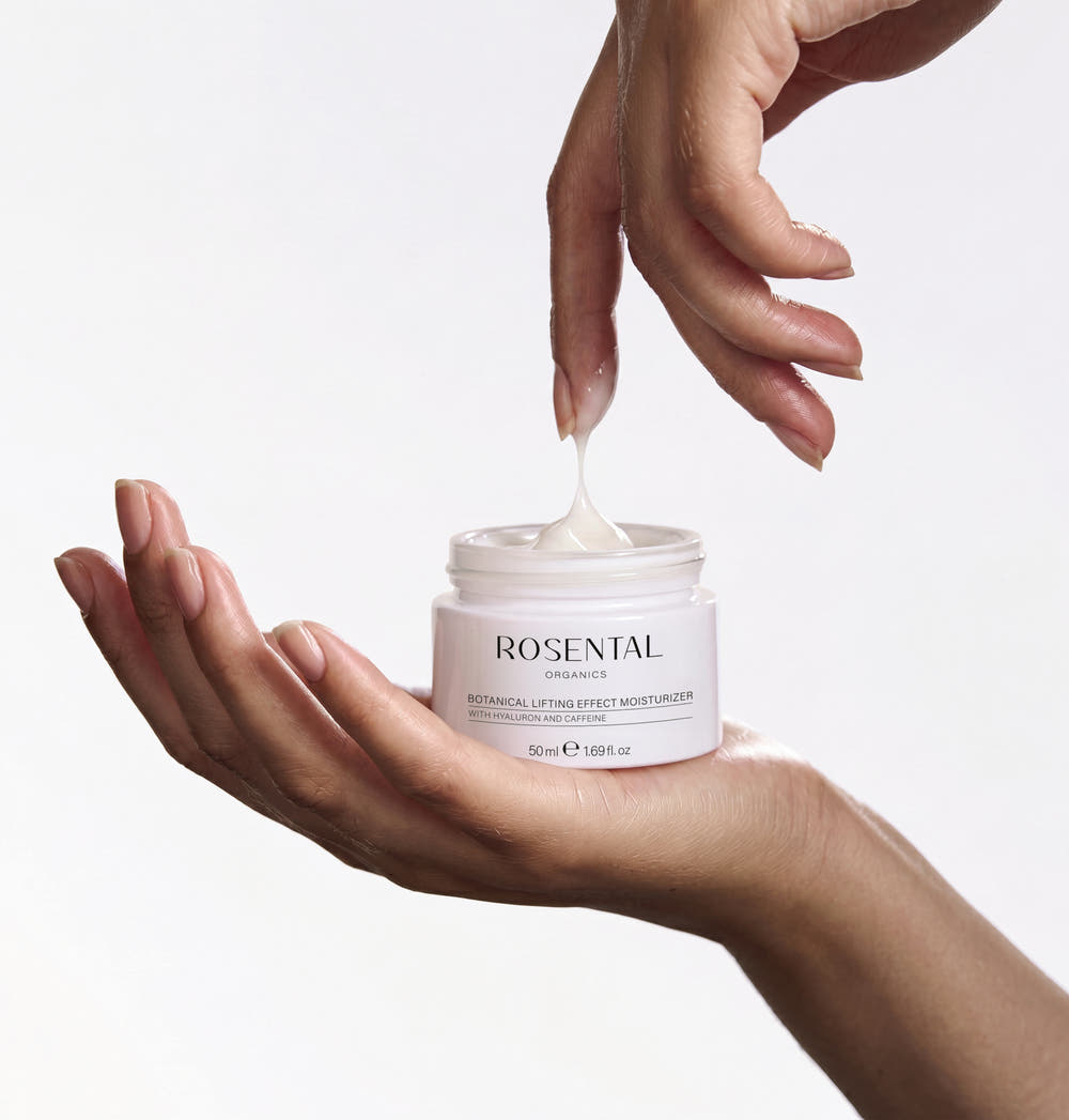 Hand hält geöffneten Tiegel Botanical Lifting Effect Moisturizer von Rosental Organics, Cremetextur zieht Faden